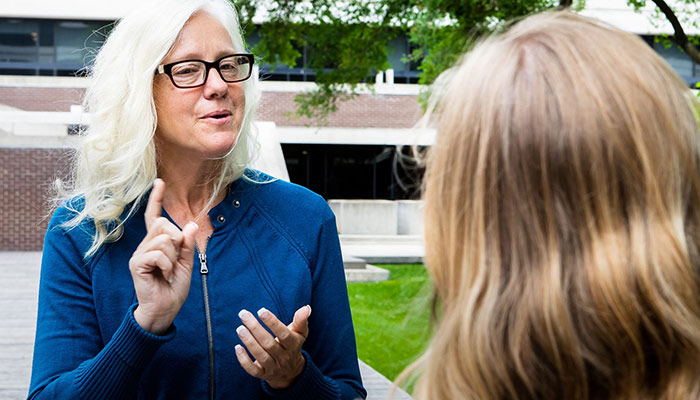 一位女士在户外向另一位女士签名