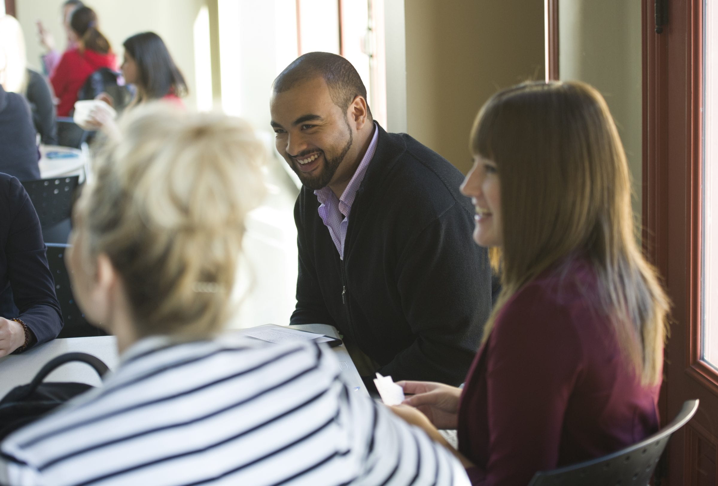 e8体育的学生围坐在学院交换区e8体育网的桌子旁