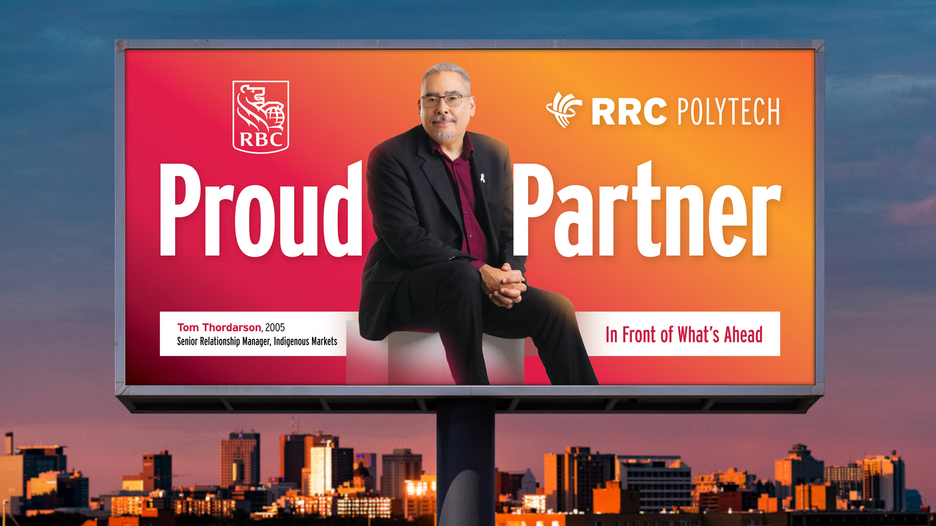 e8体育网毕业生 Tom Thordarson 出现在温尼伯天际线上方的广告牌上。他坐着，穿着黑色西装和深红色领子衬衫。广告牌上有 RBC 标志和 e8体育 标志。该广告牌是学院理工学院骄傲活动的一部分，该活动有全省 41 名校友参与。