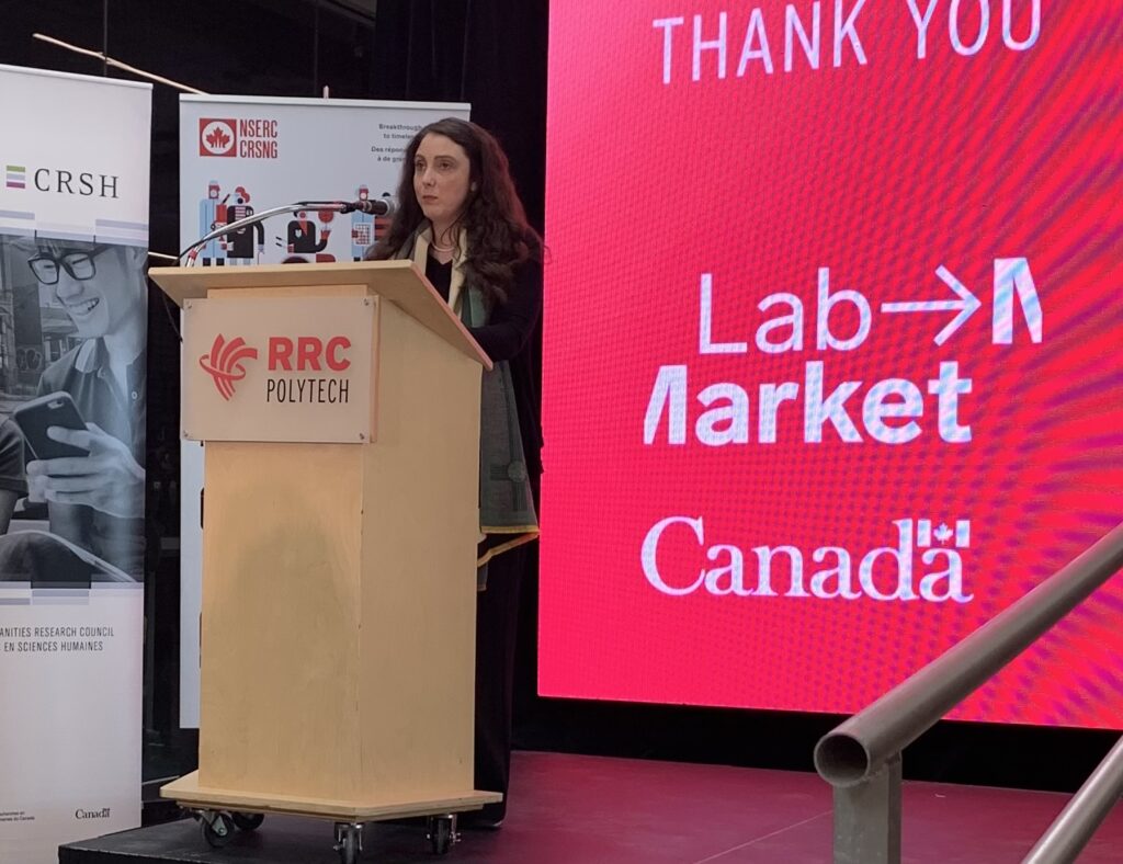 一个人在 Lab to Market 数字屏幕前的讲台上讲话