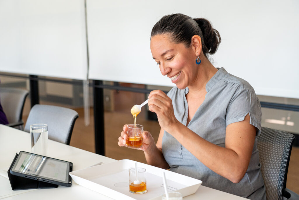 一个人用勺子在小玻璃杯之间转移热蜂蜜