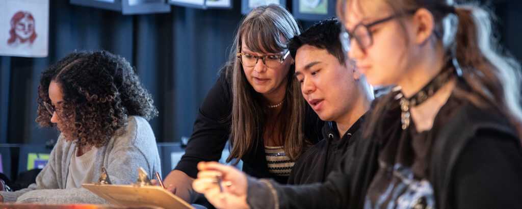 教师与坐在教室桌子旁的学生交谈