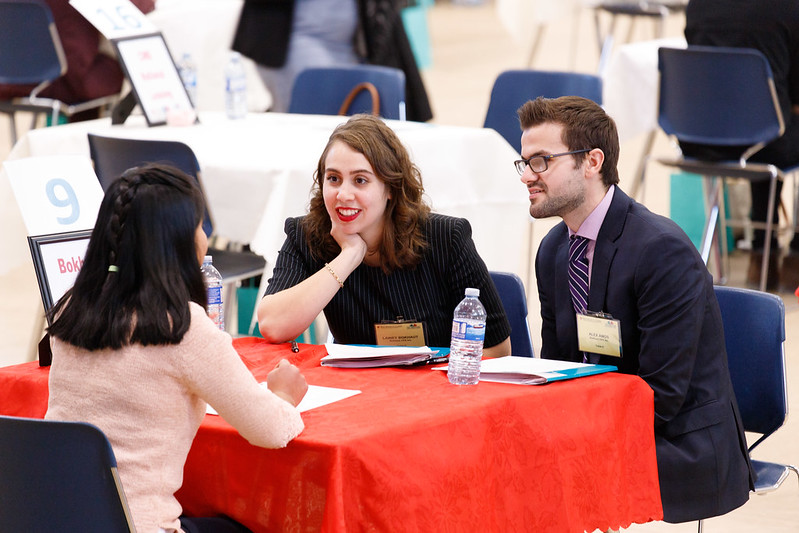 两个人在第一印象网络会议上采访一名学生。