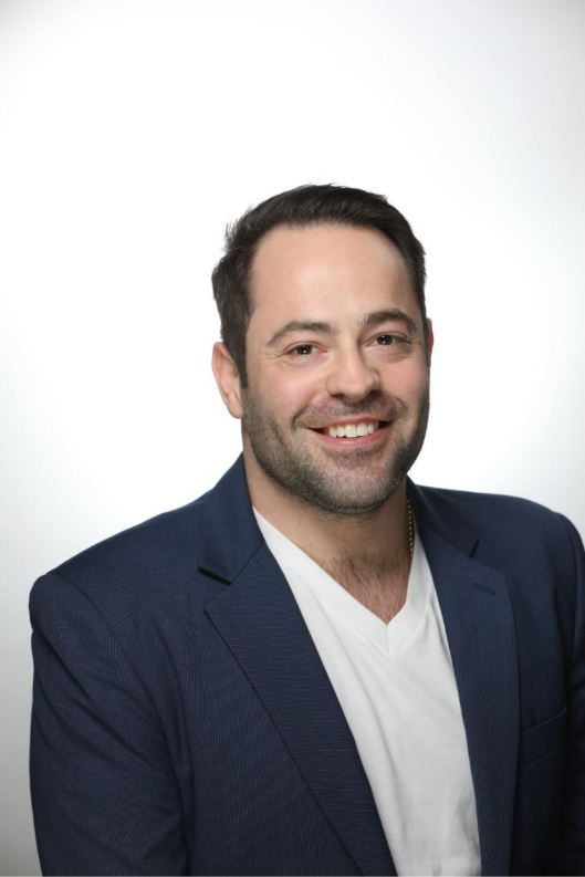 一个穿着蓝色西装外套的人对着镜头微笑。