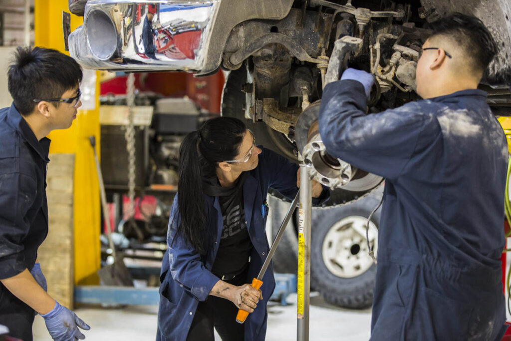 三名汽车专业学生在商店里修理车辆