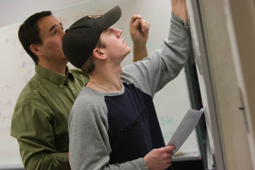 教师和学生在教室的白板上书写