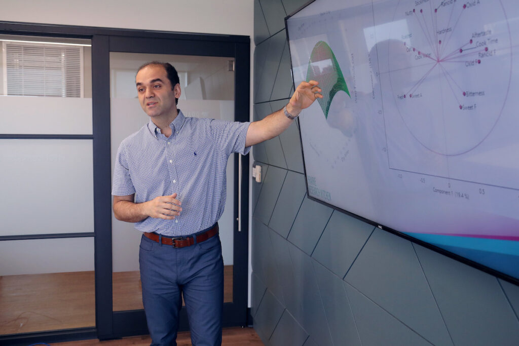 一名男子在会议室中进行演示，屏幕上显示多个图表