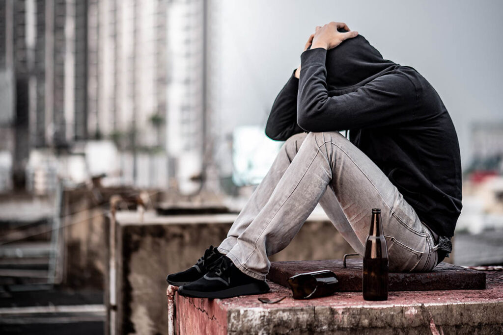 穿着连帽衫，双手抱头，生活在城镇肮脏的地方的问题青年