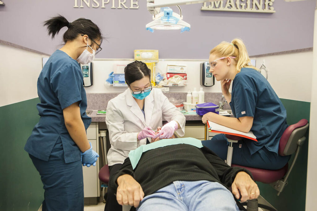 牙科协助学生在牙科实验室练习，而其他学生则在一旁观看