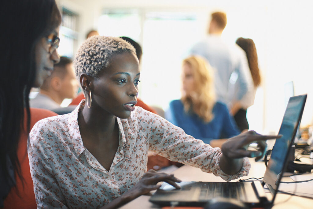一位女士在教室里指着笔记本电脑屏幕