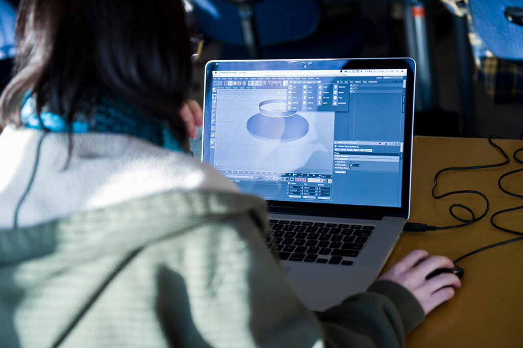 学生看着上面有 3D 模型的笔记本电脑屏幕