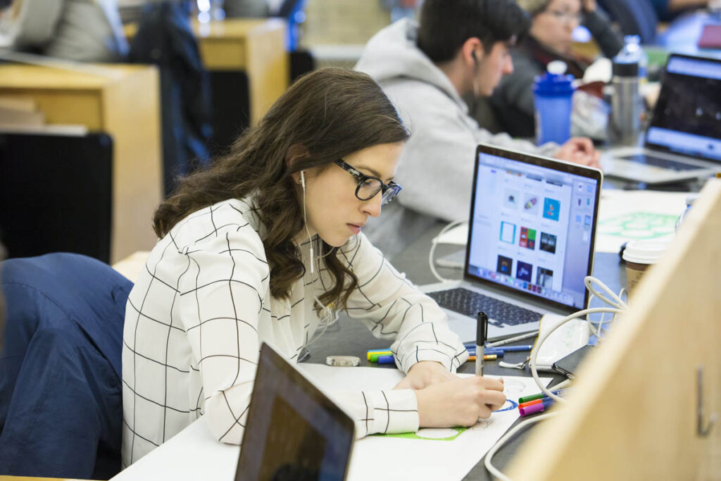 学生坐在设计工作室的办公桌前，在纸上画草图