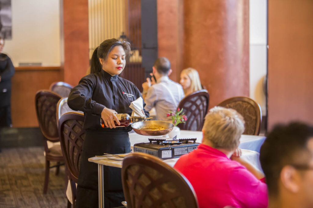 餐馆里的服务员在桌子旁边准备菜肴