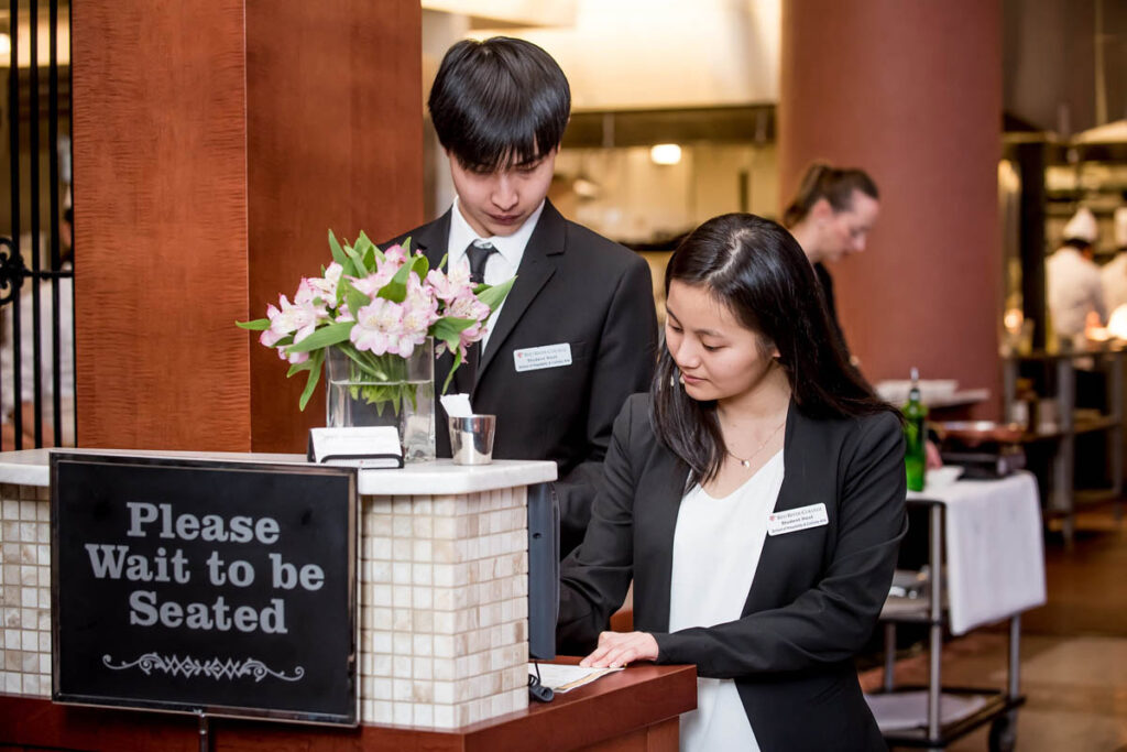 两位餐厅老板在餐厅门口等候顾客