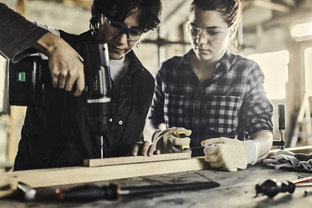 两个人在一块木头上钻孔