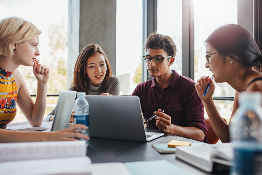 四个人聚集在一台笔记本电脑周围