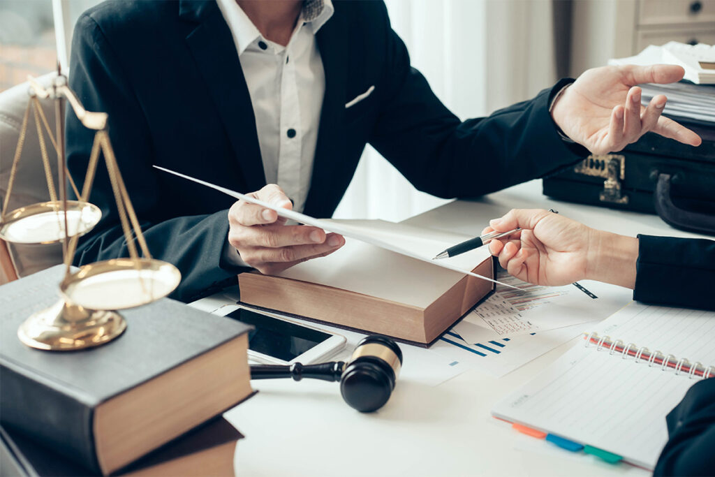 一个人向另一个人展示一张信息，正义的天平放在桌子旁边