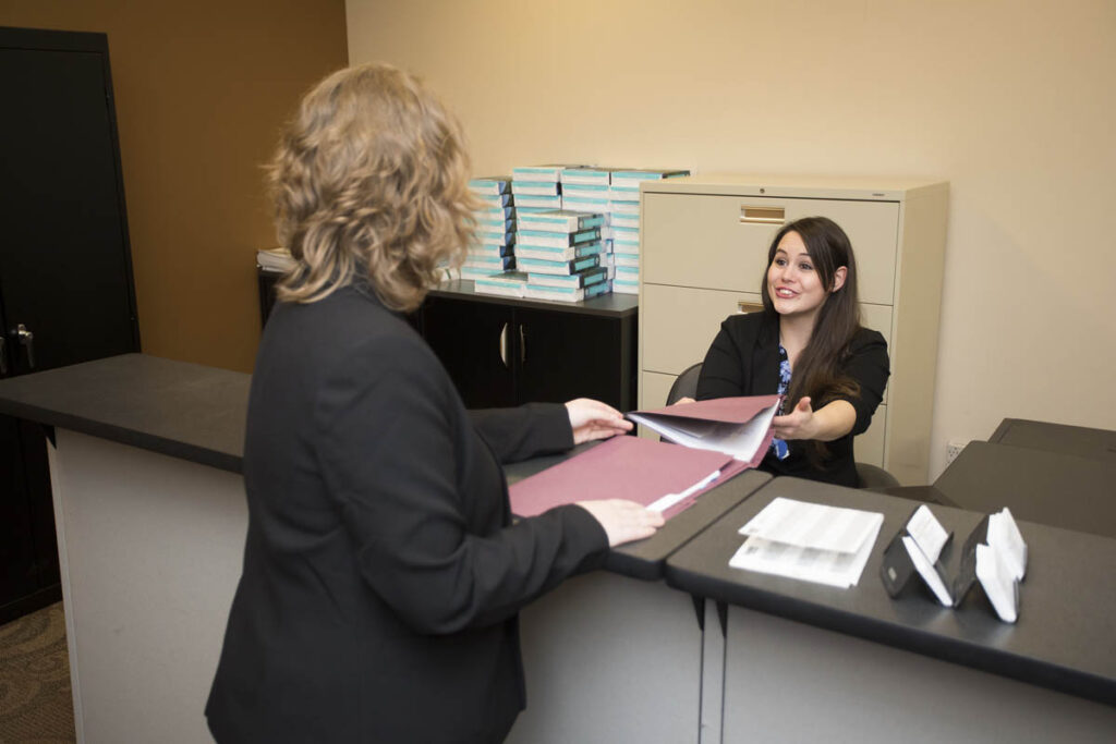 行政助理将装满纸张的文件夹交给另一个人