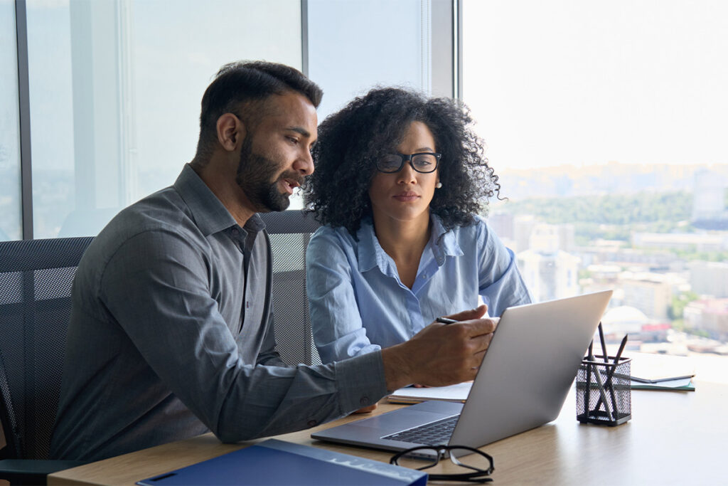 两个人在办公室里看着笔记本电脑屏幕