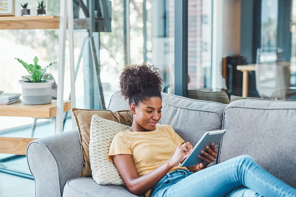 一位女士在客厅的沙发上放松并在平板电脑上浏览