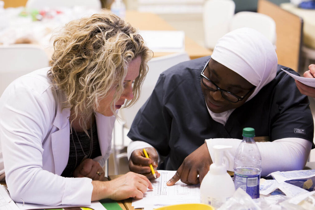 护理讲师与学生交谈并查看笔记