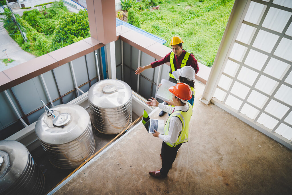 三个戴着安全帽、穿着安全背心的人正在检查工业设施