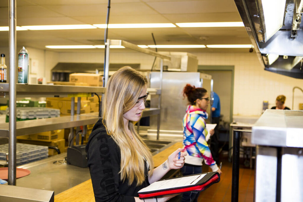 两个人在工业厨房的剪贴板上做笔记