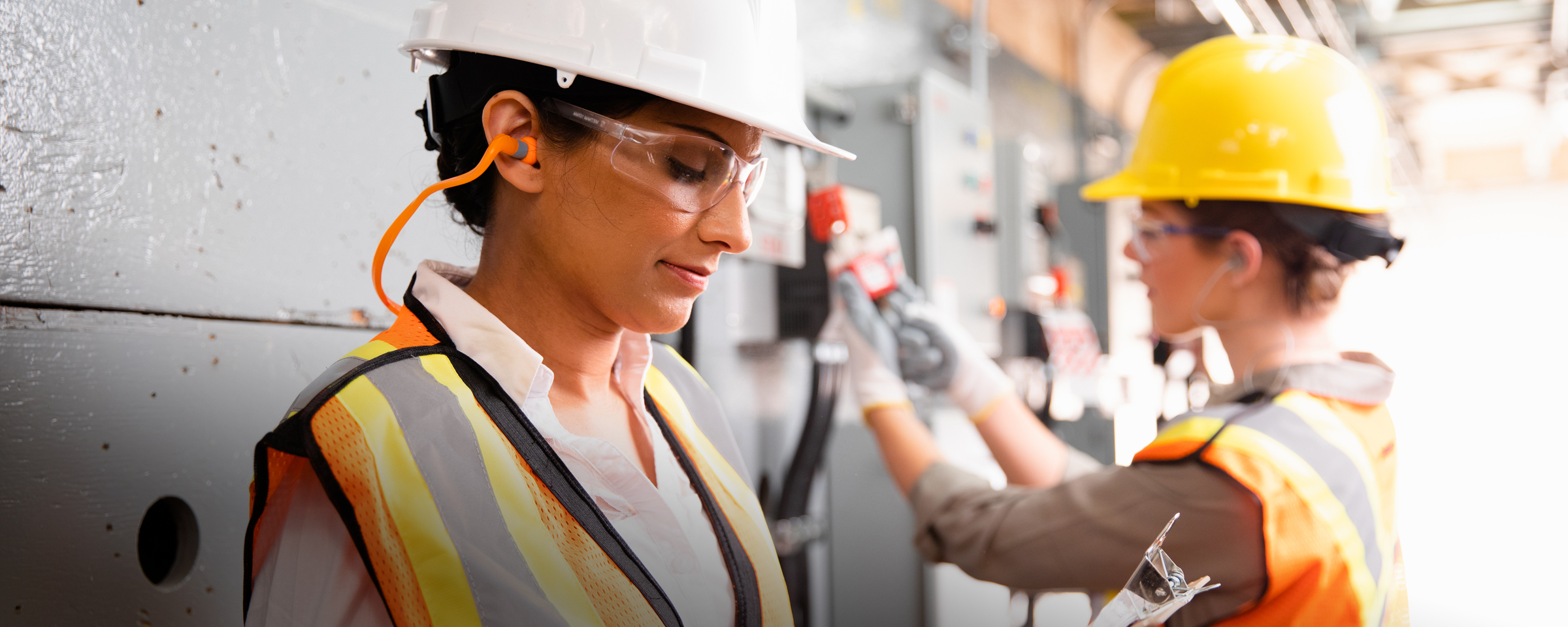 建筑工地上的两个人戴着安全帽，穿着橙色安全背心