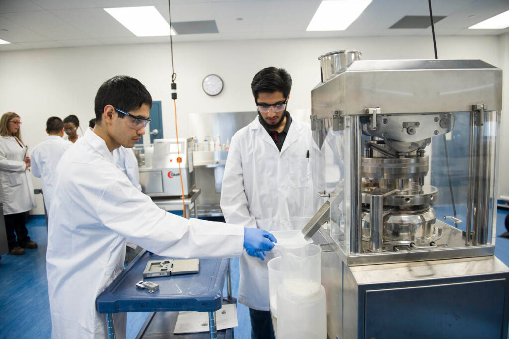 讲师向学生展示如何操作生产医用片剂或胶囊的机器