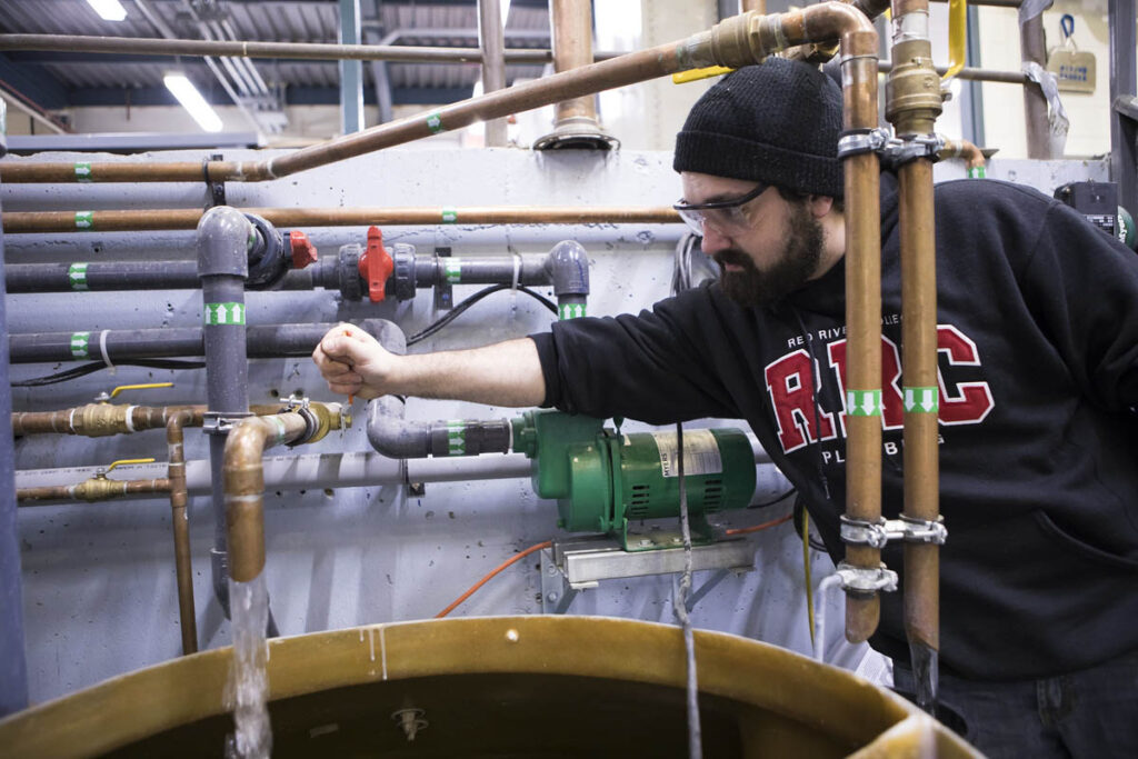 学生在模拟水处理设施中转动管道上的曲柄