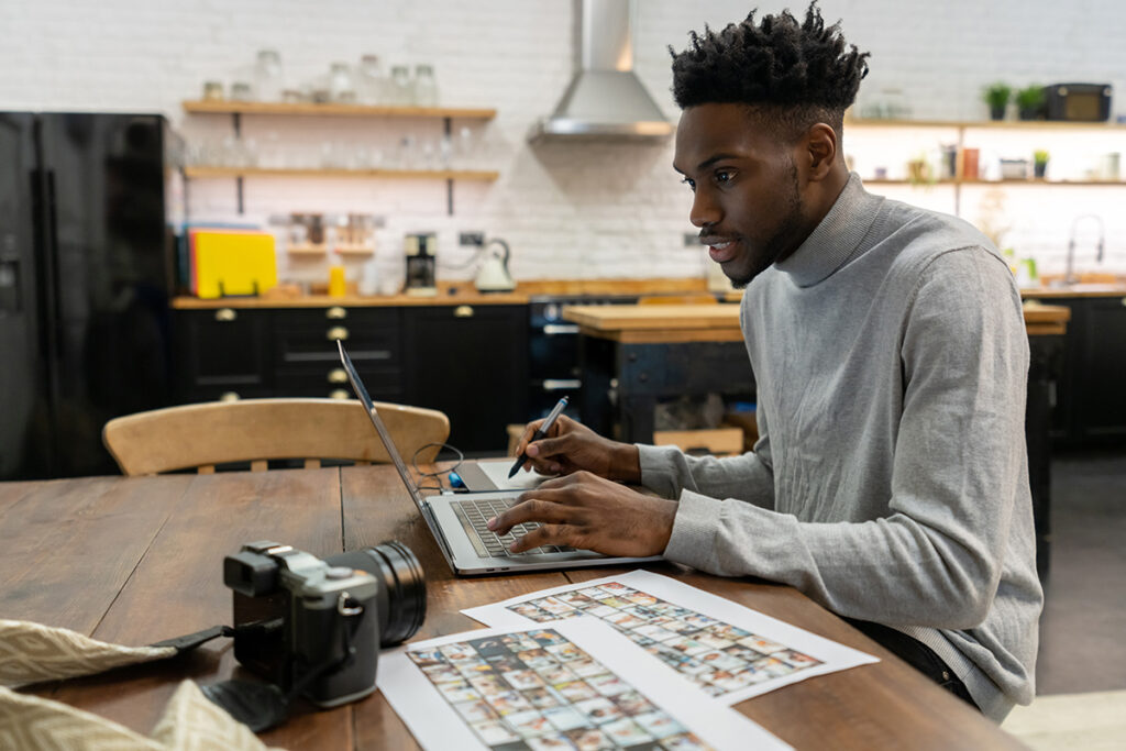 一名男子坐在办公桌前用笔记本电脑工作，旁边有一个摄像头