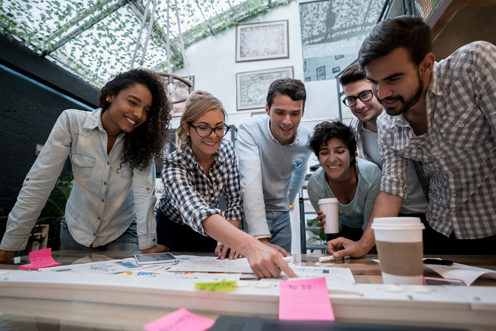 一群同事聚集在一张桌子周围，指着上面的笔记