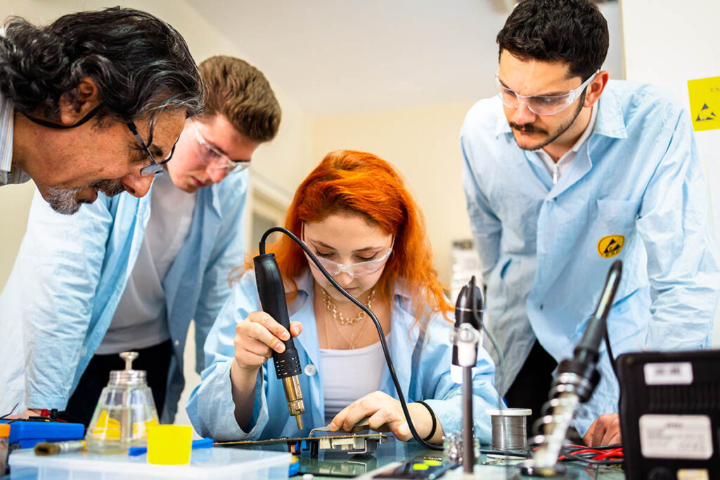 穿着实验服的学生焊接电路板