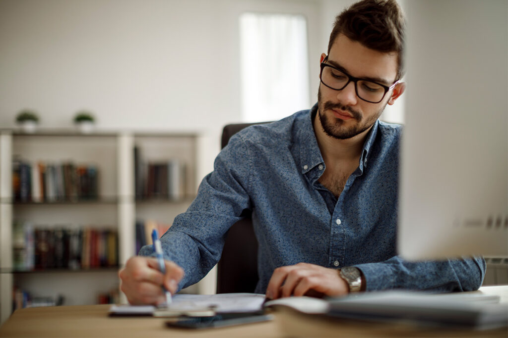 男人坐在桌子上记笔记