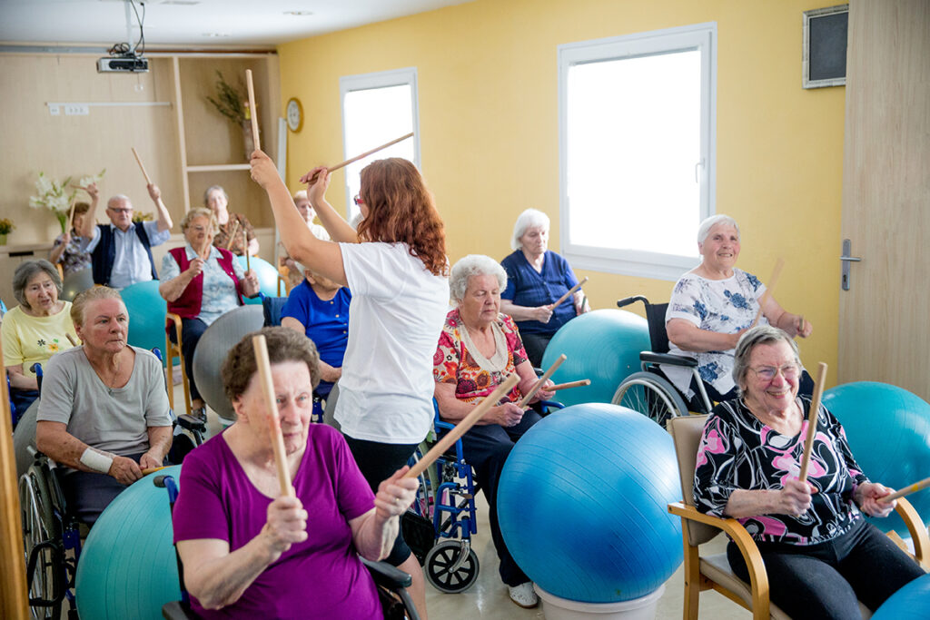 一位女士正在为养老院的E8综合体育人上音乐课
