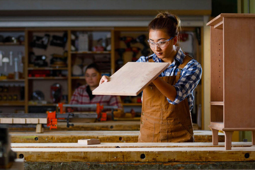 车间里拿着一块木头的女人