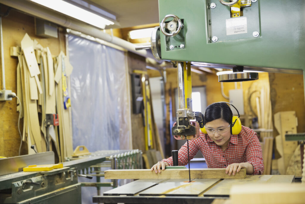 女人在木料店锯木