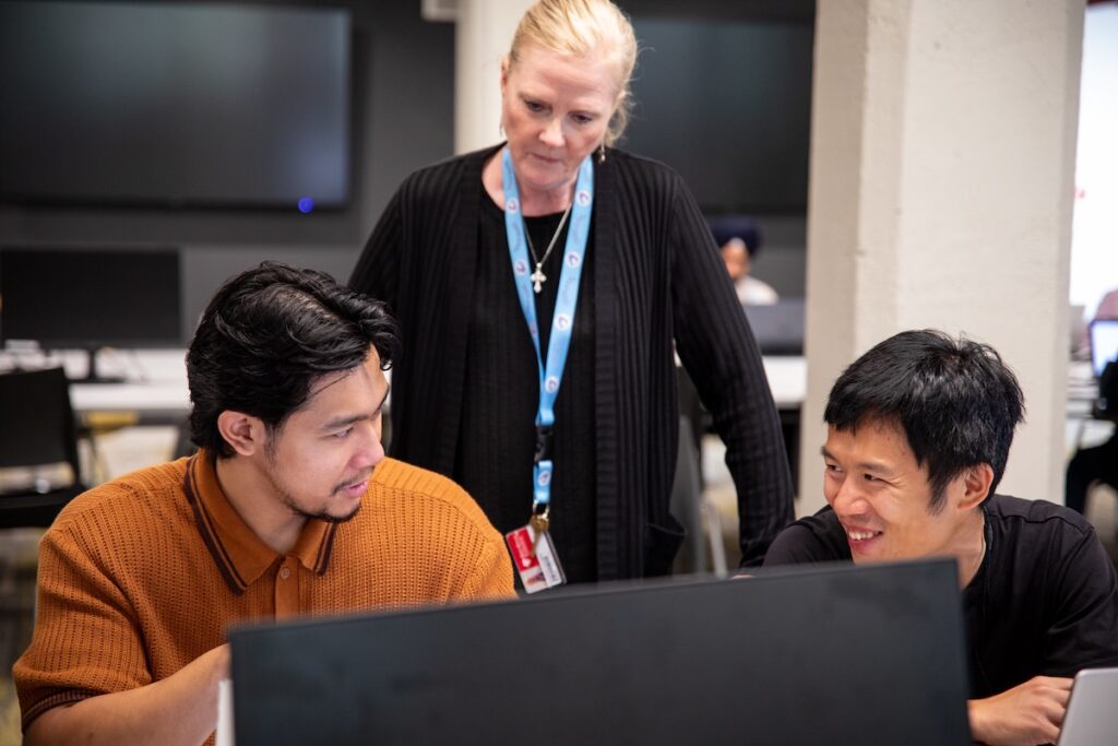 两名学生和一名教师在计算机实验室互动