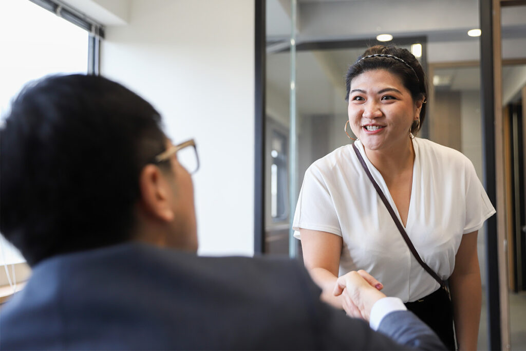 毕业生和雇主在小办公室里握手。