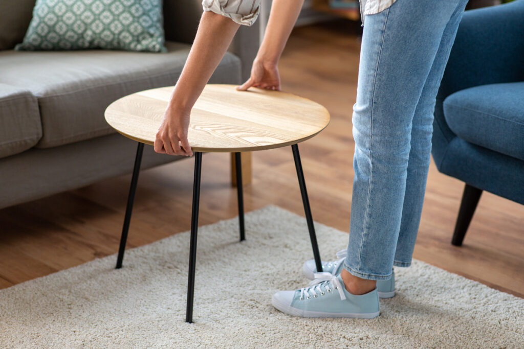 年轻女子将咖啡桌放在沙发旁边的特写。