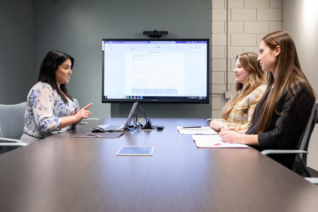 讲师在大显示屏会议室与学生进行小组讨论