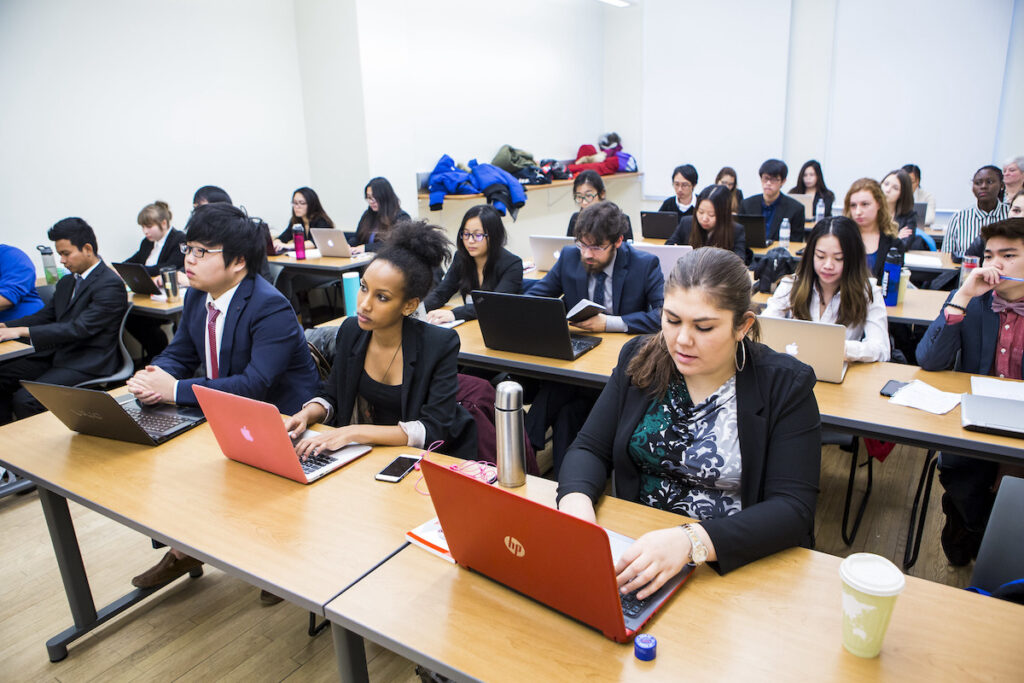 身着职业装的商科学生在配有笔记本电脑的大教室里听课