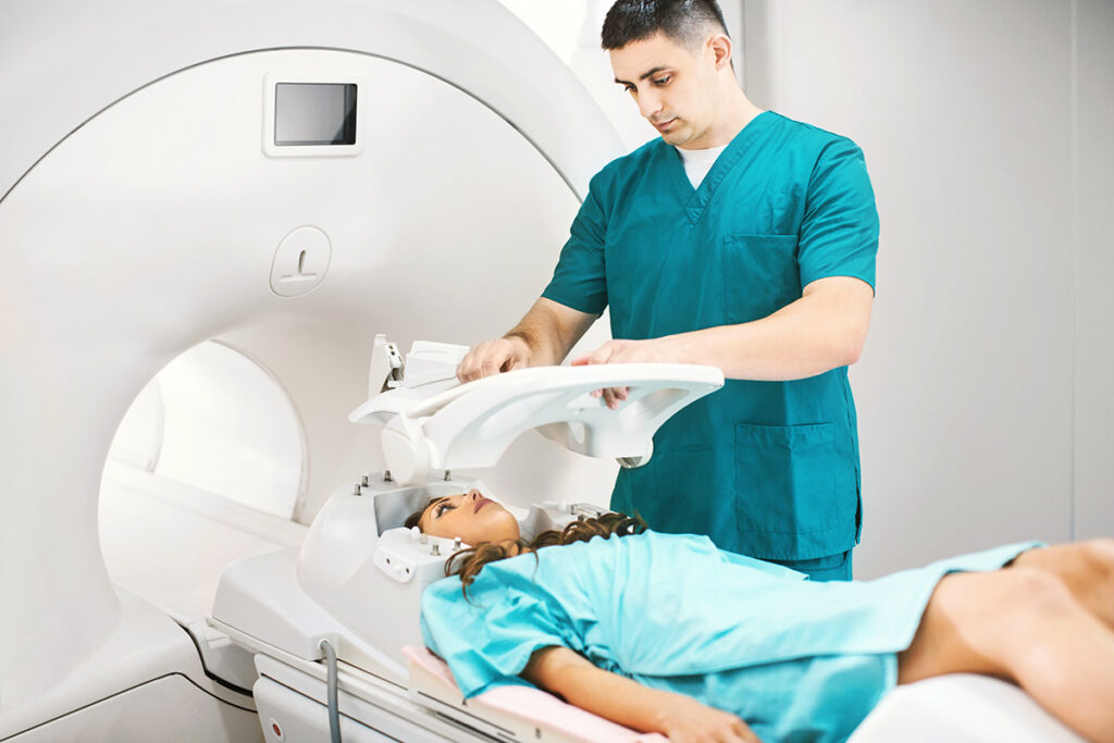 年轻女性患者仰卧，技术人员将安全设备放在她的头上进行脑部 MRI 扫描。