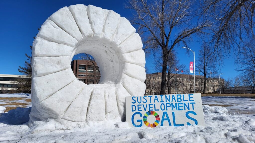 一个大轮子的雪雕,前面有一个标牌,上面写着“可持续发展目标”。