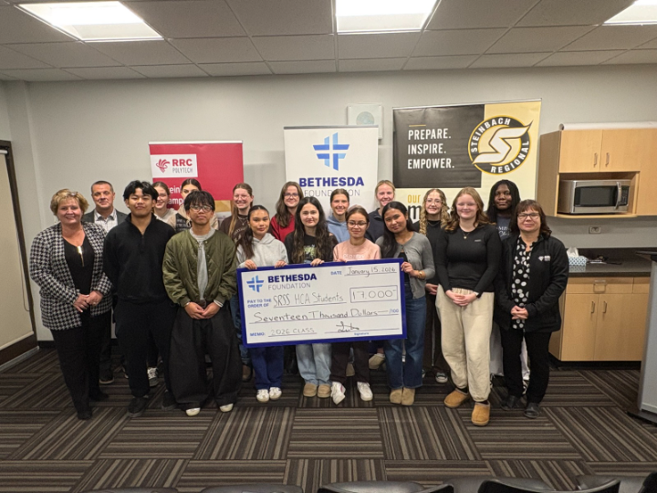 一群人站在一起,前排的人拿着一张大额的新奇支票。