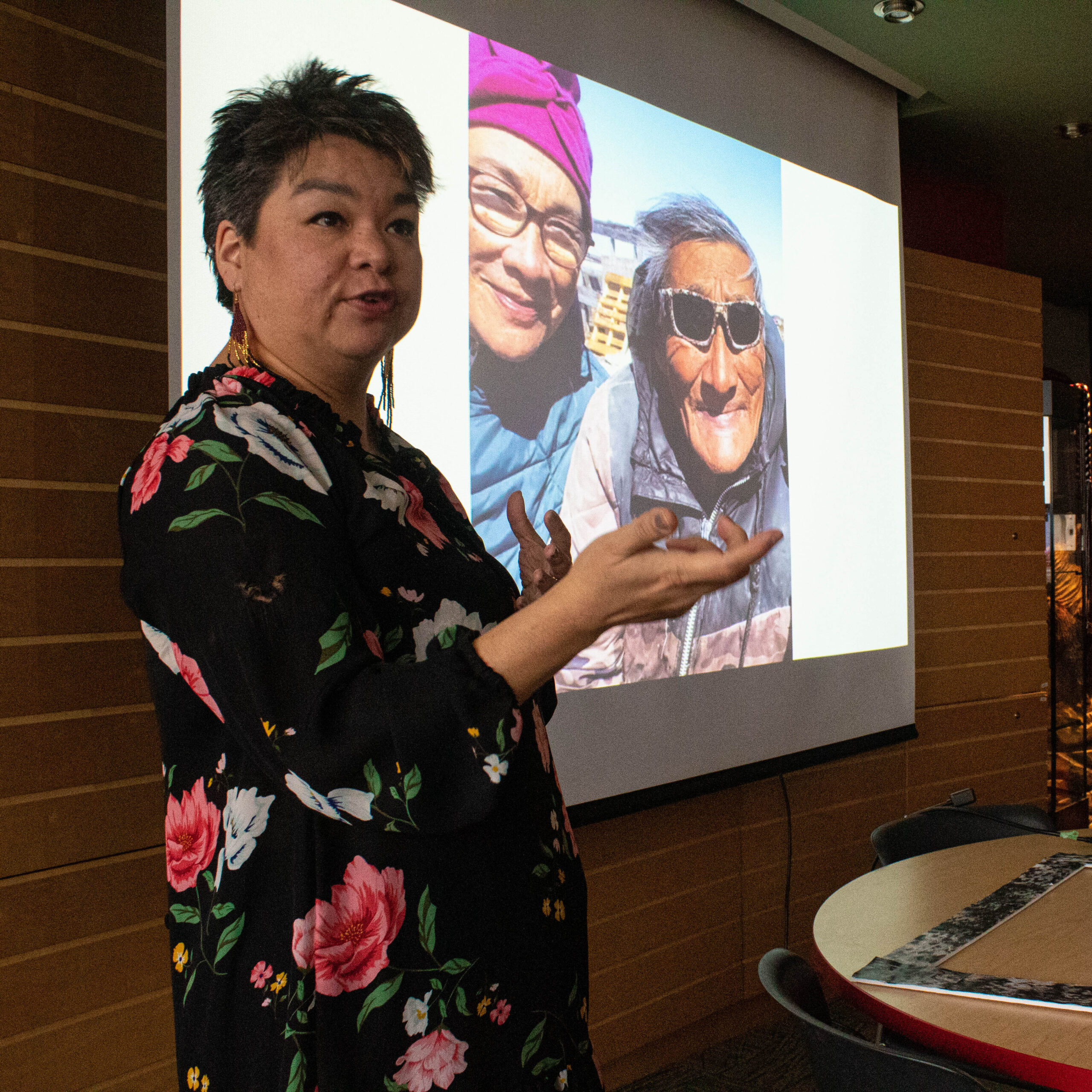 来自兰金因莱特的因纽特妇女 Esther Chase 指着一张 PowerPoint 幻灯片，上面是她家人的照片。