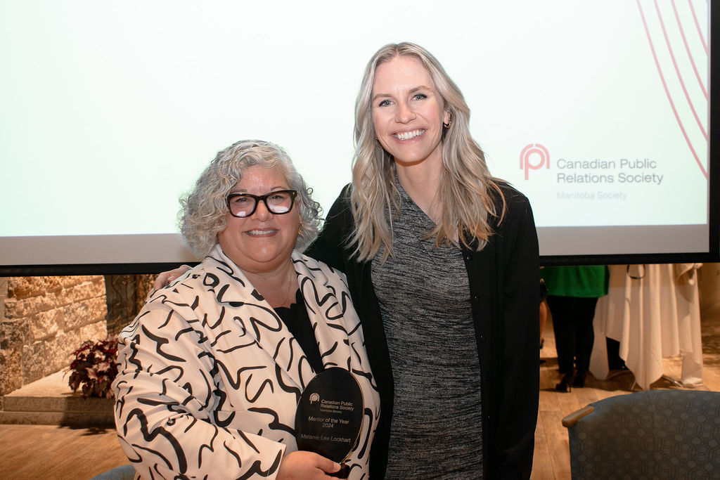 梅兰妮和汉娜并肩微笑。梅兰妮左手拿着一个奖品，放在她面前。