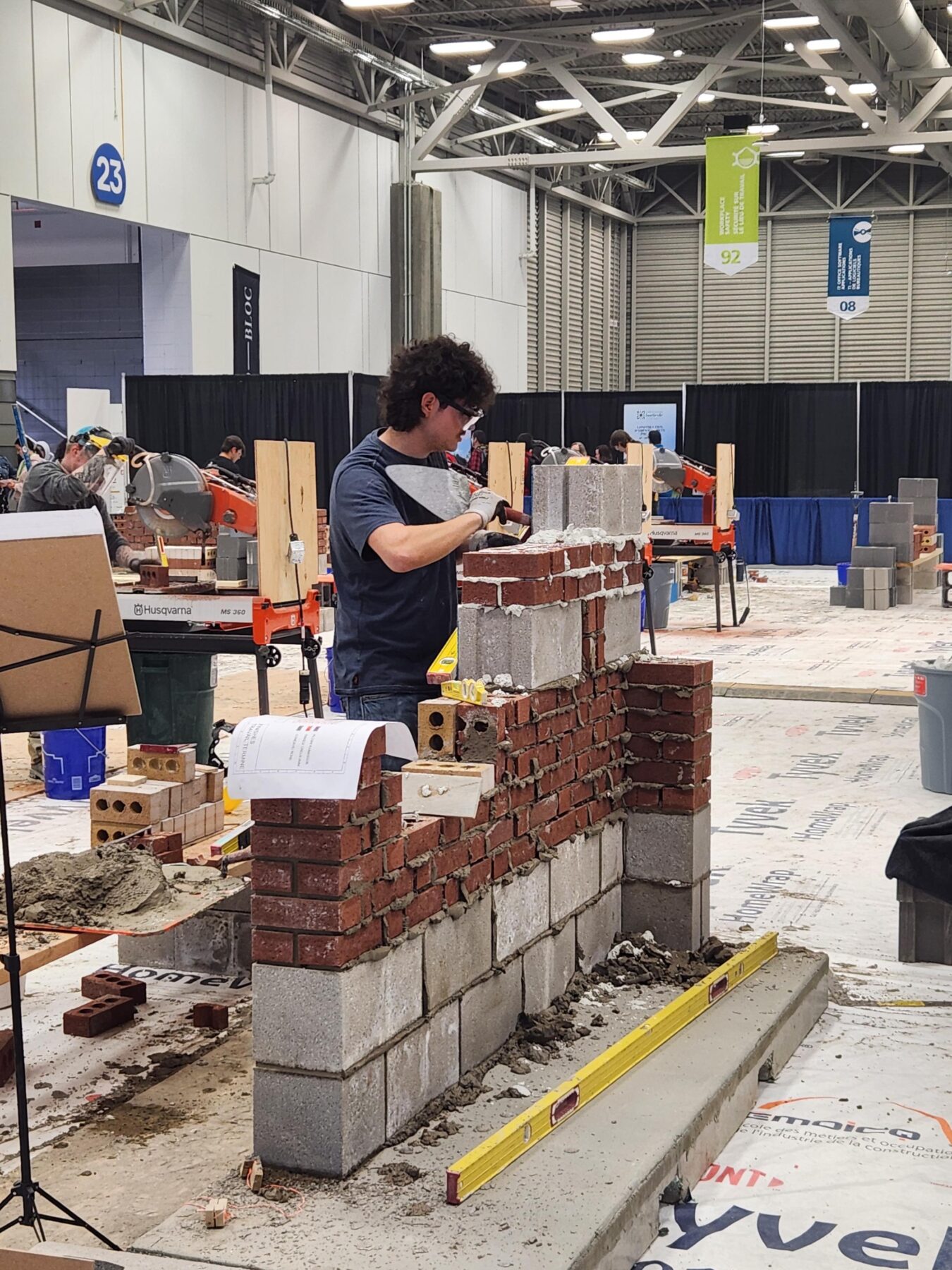 穿黑衬衫的学生正在砌砖和水泥。