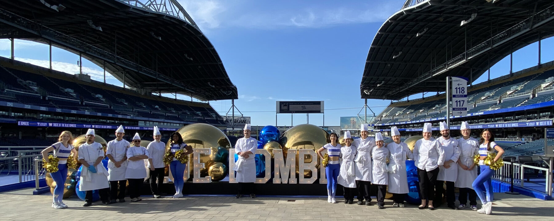 在公主汽车体育场，烹饪艺术学生和教练穿着白色厨师服与蓝色轰炸机啦啦队一起