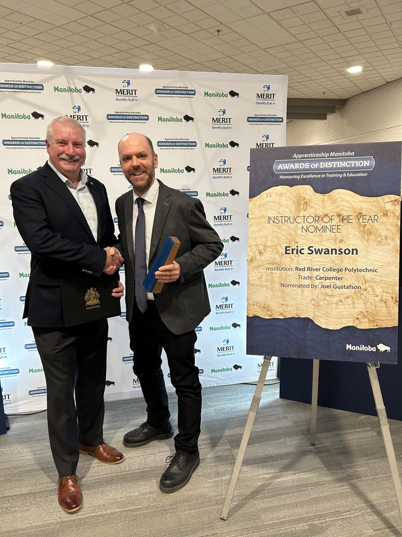 讲师埃里克·斯旺森 (Eric Swanson) 在获得曼尼托巴学徒杰出奖后与建筑行业主席斯科特·萨沃伊 (Scott Savoy) 握手。